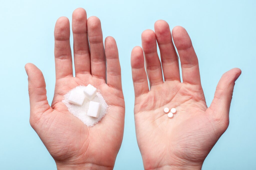 sugar cubes in one hand and artificial sweetener in the other