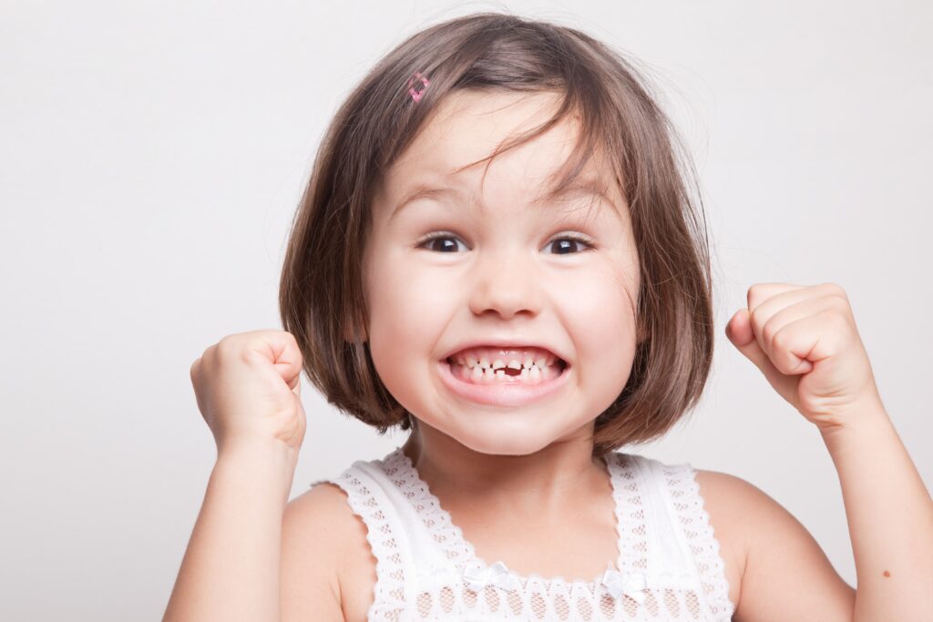 young girl smiling with missing front tooth